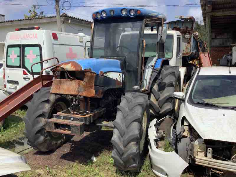 Trator agrícola azul avaliado em processo de perícia técnica para verificar falhas estruturais e segurança operacional.