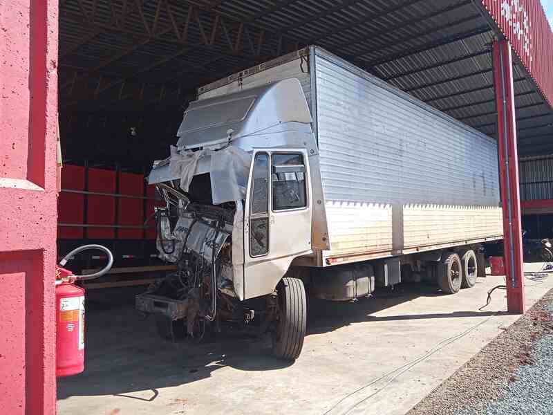 Caminhão danificado em acidente, inspecionado durante perícia técnica para identificação de falhas e causas do impacto.