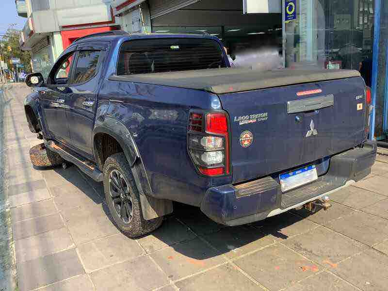 Caminhonete Mitsubishi L200 Triton azul inspecionada para perícia de falha técnica em suspensão dianteira.