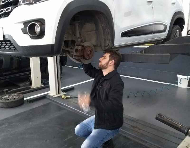 Perito judicial Carlos Eduardo Bruxel examinando sistema de freios de veículo Renault em elevador na cidade de Rio Grande/RS, destacando competência em perícias técnicas de manutenção automotiva.
