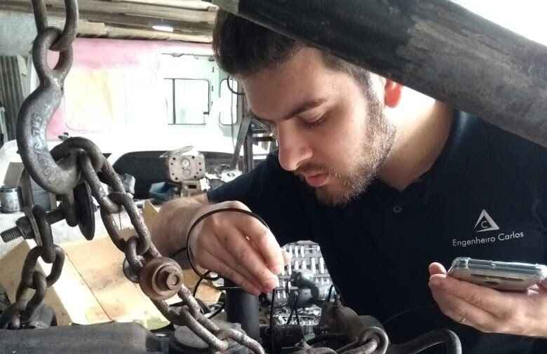 Perito judicial Carlos Eduardo Bruxel inspecionando motor diesel Scania de caminhão na cidade de Pelotas/RS com equipamentos técnicos, representando expertise em diagnósticos automotivos e perícias técnicas.