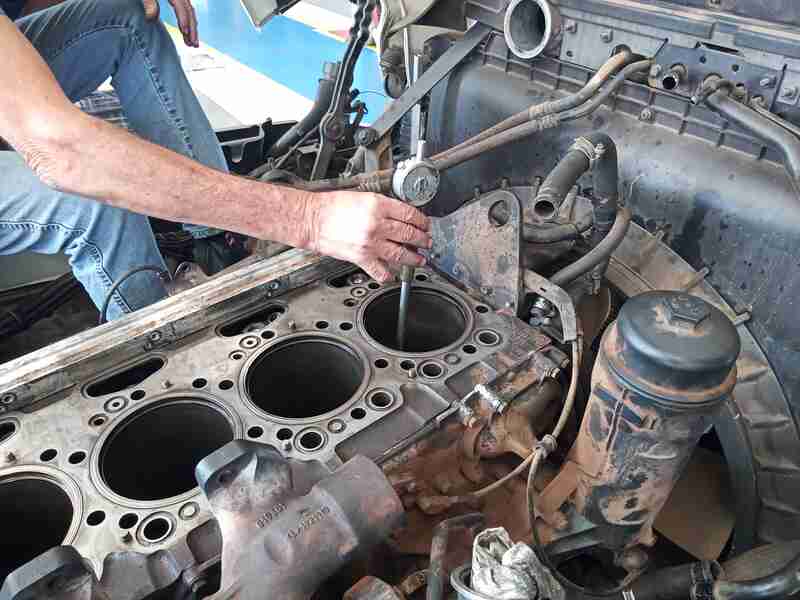 Técnico realizando medições em motor de caminhão desmontado para perícia técnica e análise de vício oculto