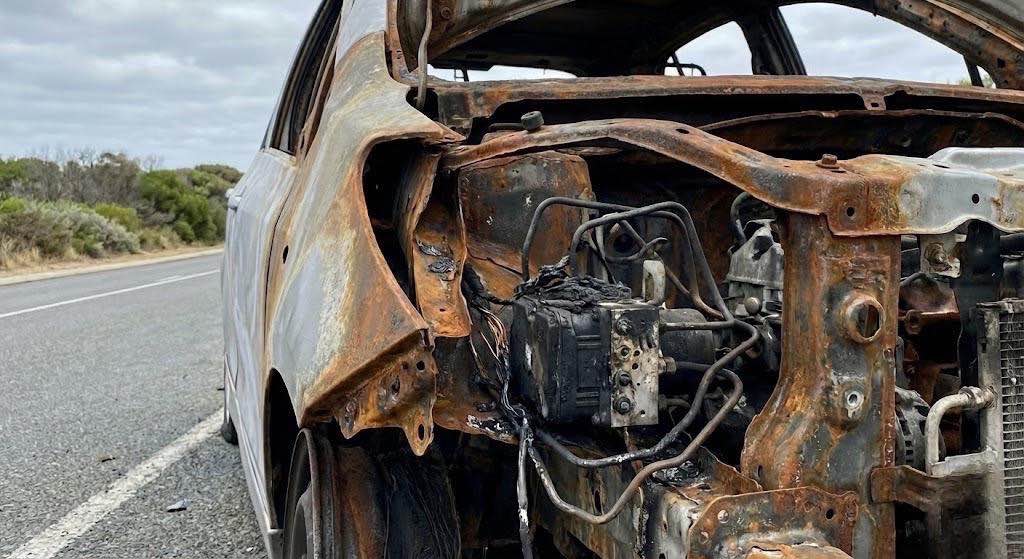 Detalhe técnico de perícia de incêndio veicular em veículo incendiado após colisão em Imbé RS, destacando o módulo ABS e fiações rompidas.