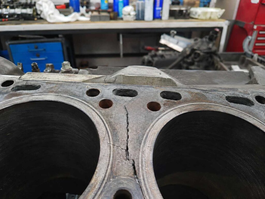 Laudo pericial de engenharia mecânica demonstrando falha em retífica de motor diesel em Três Coroas - RS, evidenciando uma trinca estrutural visível no bloco de metal entre os cilindros.