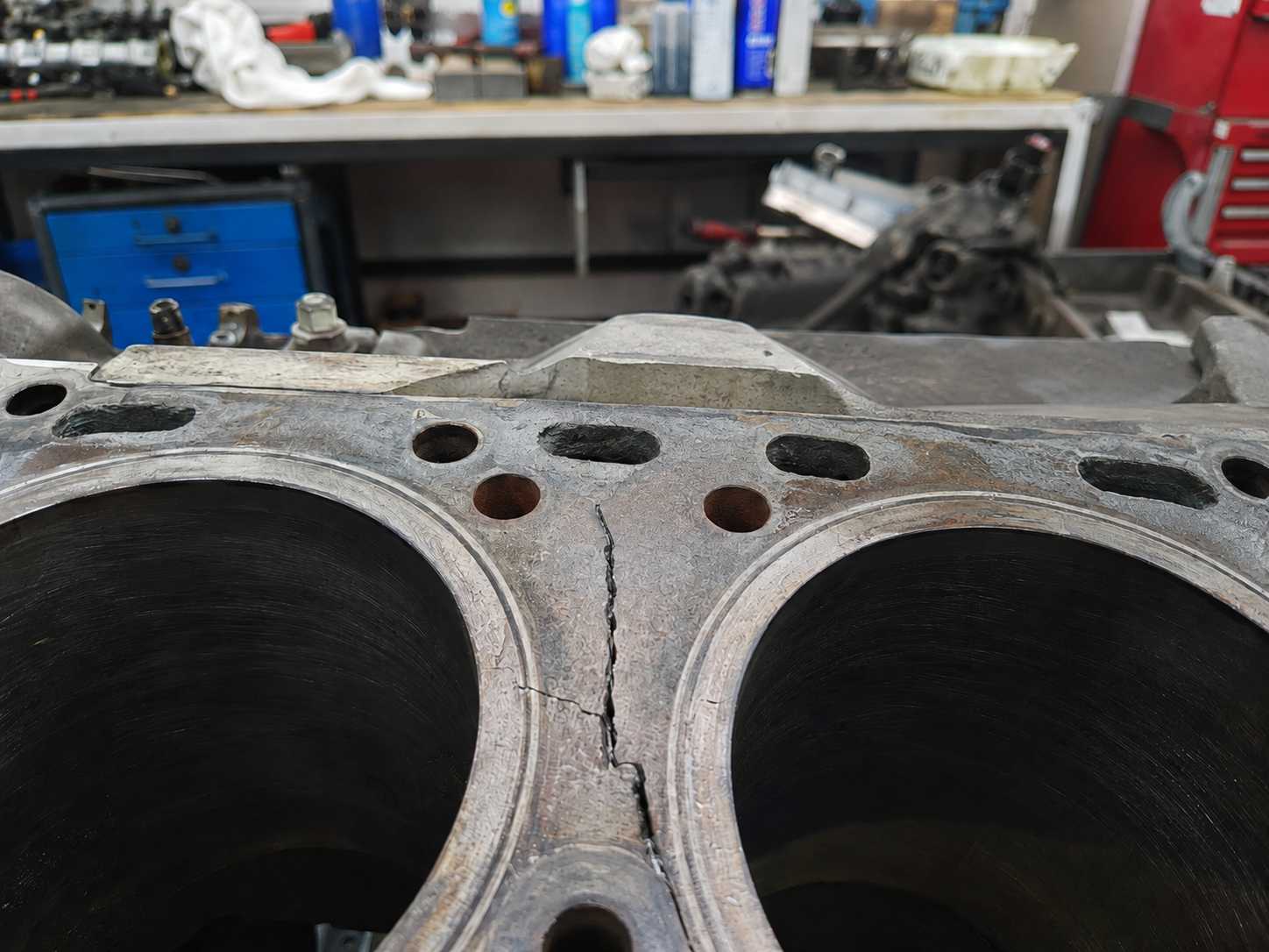 Laudo pericial de engenharia mecânica demonstrando falha em retífica de motor diesel em Três Coroas - RS, evidenciando uma trinca estrutural visível no bloco de metal entre os cilindros.
